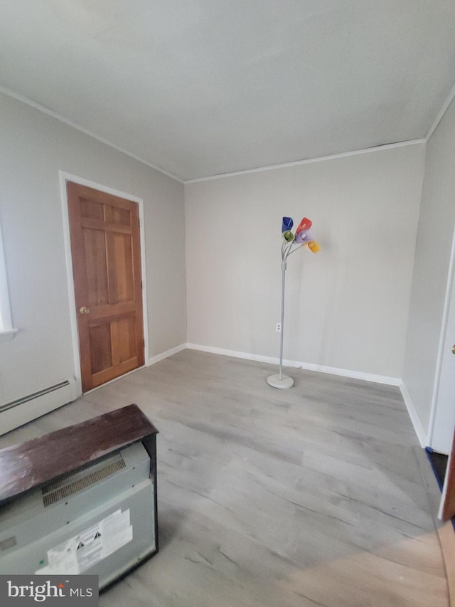 interior space featuring crown molding, baseboards, a baseboard radiator, and wood finished floors
