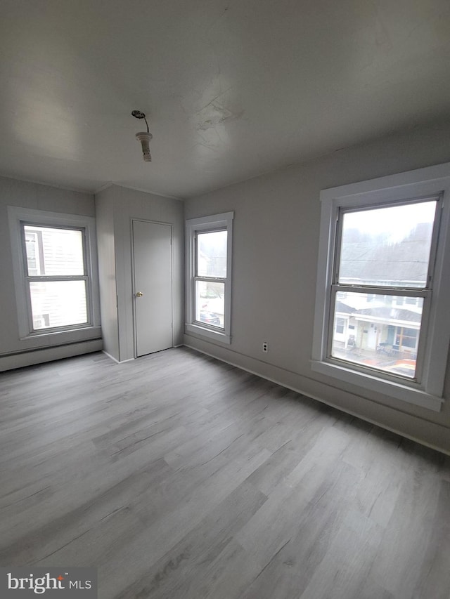 unfurnished bedroom featuring a baseboard radiator, wood finished floors, and baseboards