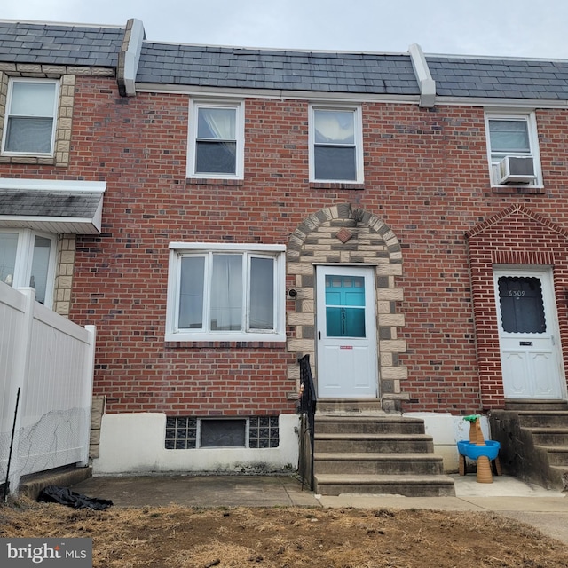 townhome / multi-family property with brick siding, mansard roof, entry steps, fence, and cooling unit