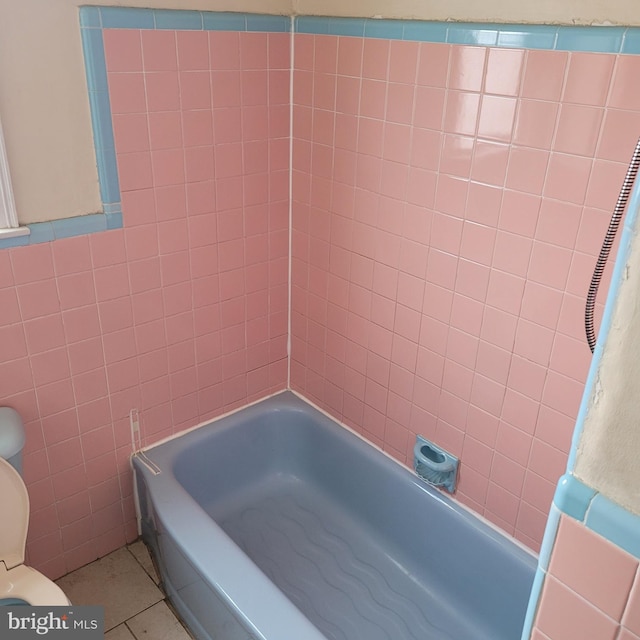 bathroom featuring toilet, tile patterned flooring, and tile walls