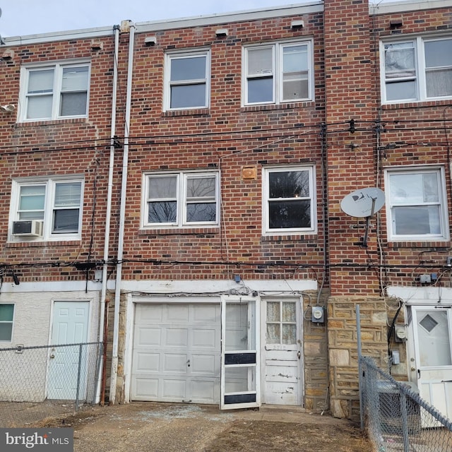 view of property with a garage, cooling unit, brick siding, and fence