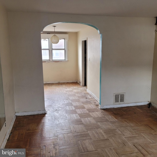 spare room with arched walkways, visible vents, and baseboards