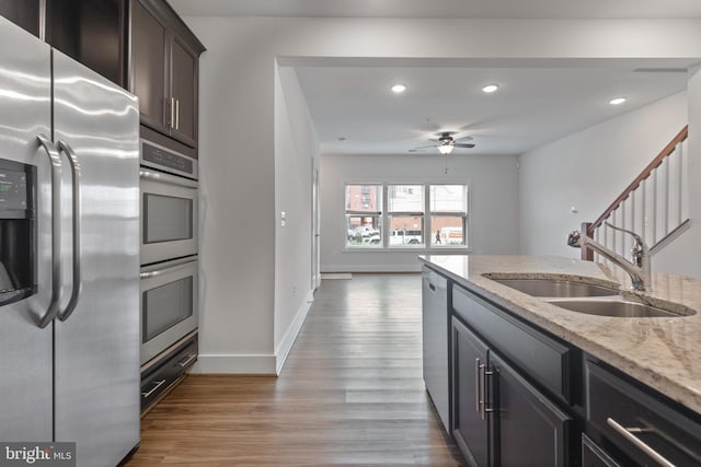 kitchen featuring light stone counters, light wood finished floors, recessed lighting, a sink, and appliances with stainless steel finishes