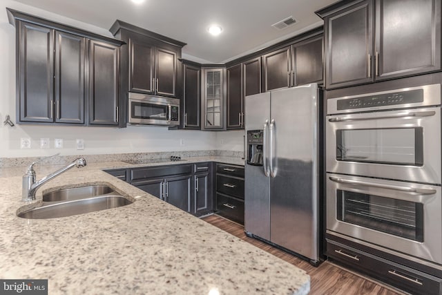 kitchen with visible vents, light stone countertops, dark wood finished floors, appliances with stainless steel finishes, and a sink