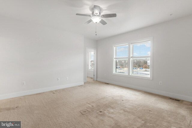 empty room featuring visible vents, baseboards, carpet, and a ceiling fan