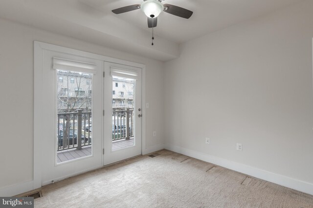 carpeted spare room featuring visible vents, baseboards, and a ceiling fan