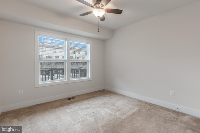 spare room with carpet flooring, visible vents, baseboards, and ceiling fan