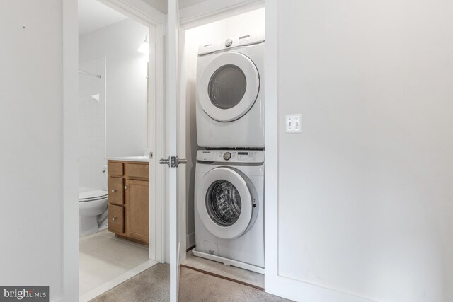 washroom with stacked washer / dryer, light colored carpet, and laundry area