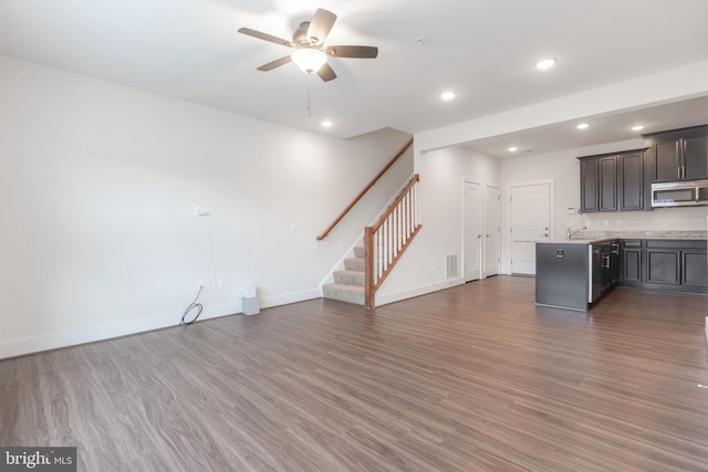 unfurnished living room with visible vents, baseboards, ceiling fan, stairway, and wood finished floors