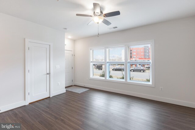 unfurnished room featuring visible vents, baseboards, ceiling fan, and dark wood-style flooring