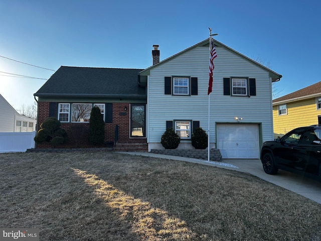 split level home with fence, a chimney, concrete driveway, a garage, and brick siding