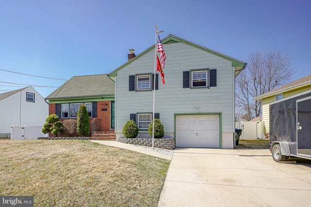 tri-level home with an attached garage, fence, a front yard, driveway, and a gate