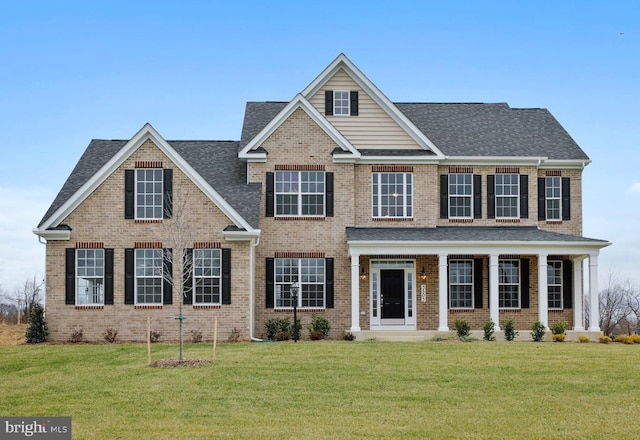 view of front of property with brick siding, a front lawn, and roof with shingles