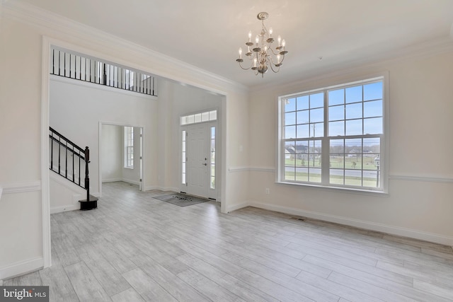 foyer entrance with crown molding, stairway, a chandelier, and wood finished floors