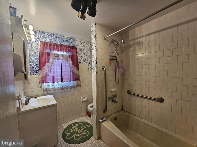 bathroom with toilet, tile patterned floors, tub / shower combination, vanity, and tile walls