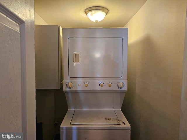 clothes washing area featuring stacked washer and clothes dryer and laundry area