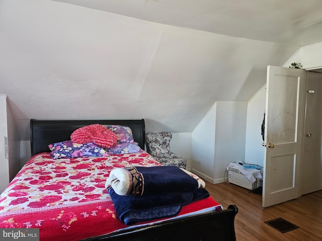 bedroom featuring lofted ceiling, visible vents, and wood finished floors