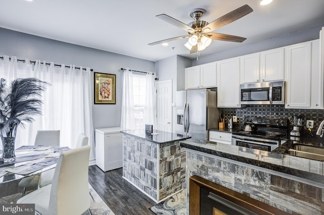 kitchen with dark stone counters, a sink, appliances with stainless steel finishes, white cabinetry, and tasteful backsplash