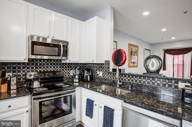 kitchen featuring a sink, tasteful backsplash, dark stone counters, appliances with stainless steel finishes, and white cabinets