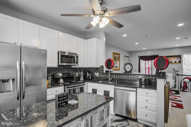 kitchen featuring backsplash, appliances with stainless steel finishes, a peninsula, and a sink