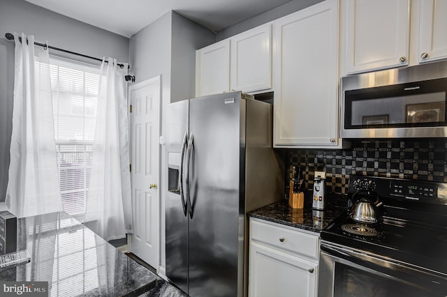 kitchen featuring dark stone counters, backsplash, appliances with stainless steel finishes, and white cabinetry