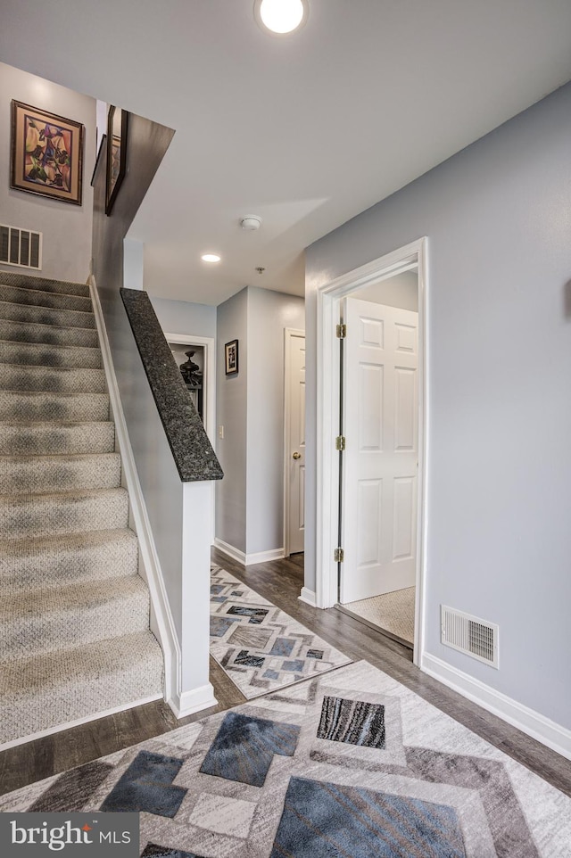 foyer featuring stairs, baseboards, visible vents, and dark wood-style flooring