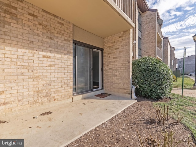 doorway to property featuring brick siding and a patio area