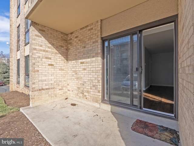 property entrance with brick siding and a patio