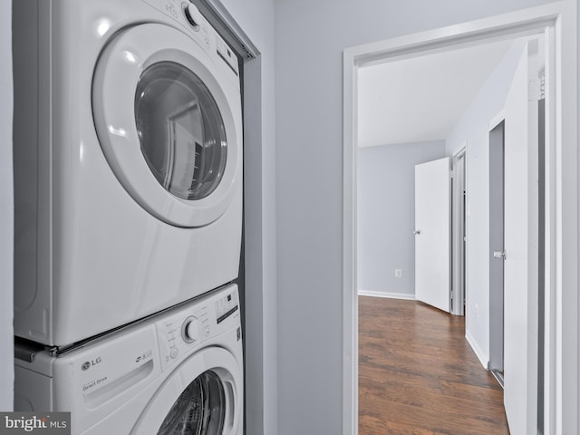 laundry room with laundry area, baseboards, dark wood-type flooring, and stacked washer / dryer