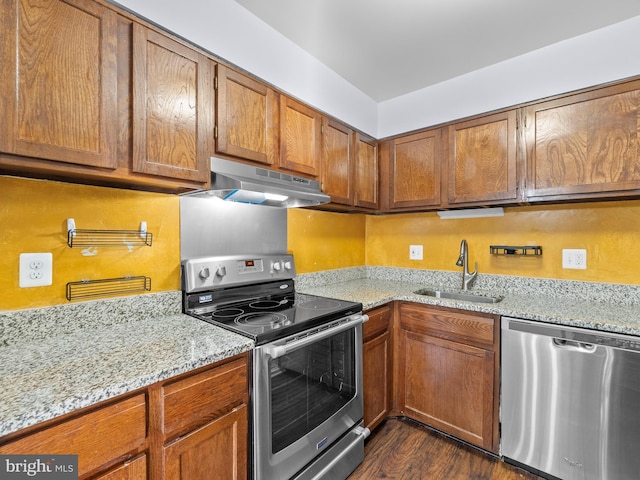 kitchen featuring stainless steel appliances, brown cabinets, a sink, and under cabinet range hood