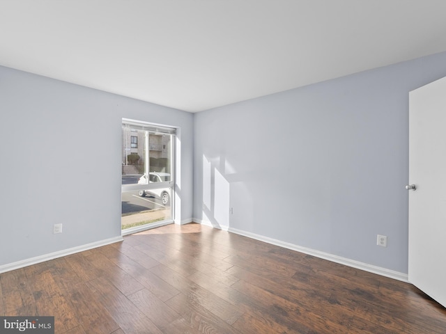 spare room featuring baseboards and wood finished floors