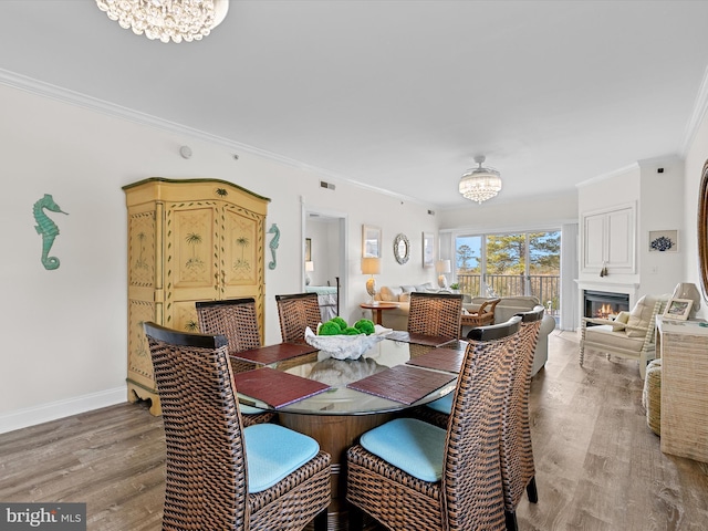 dining area featuring crown molding, a notable chandelier, and wood finished floors