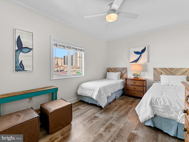 bedroom with crown molding, a view of city, a ceiling fan, and wood finished floors