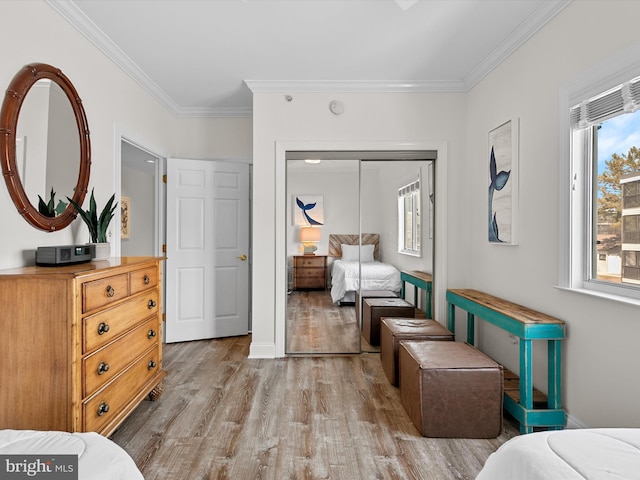 bedroom with baseboards, light wood finished floors, a closet, and crown molding