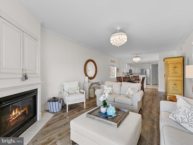 living room with baseboards, a fireplace with flush hearth, ornamental molding, an inviting chandelier, and light wood-style floors