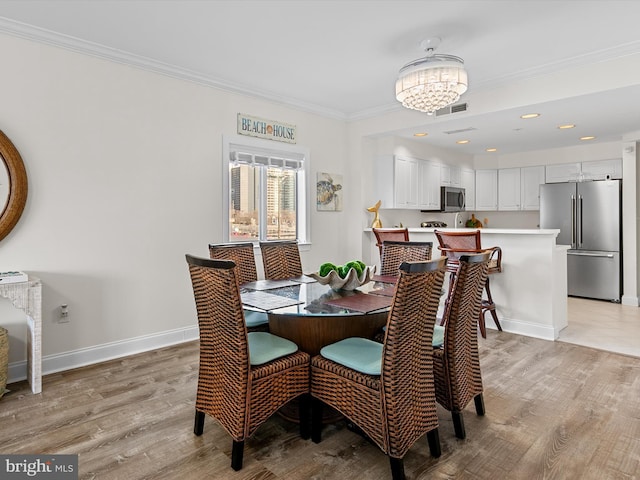 dining space featuring light wood finished floors, visible vents, ornamental molding, a chandelier, and baseboards