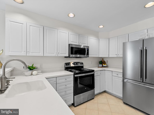 kitchen featuring stainless steel appliances, a sink, light countertops, and white cabinets