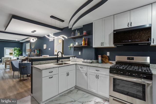 kitchen with stainless steel gas stove, a sink, under cabinet range hood, a peninsula, and white cabinets