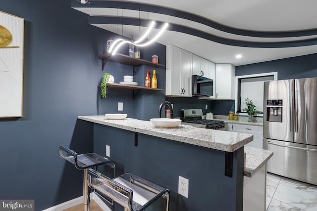 kitchen with marble finish floor, a breakfast bar, white cabinetry, appliances with stainless steel finishes, and a peninsula