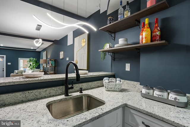 kitchen featuring white cabinetry, open shelves, light stone counters, and a sink