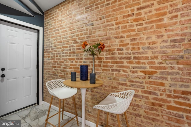 interior space featuring marble finish floor and brick wall