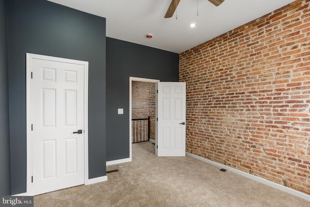 unfurnished bedroom featuring ceiling fan, baseboards, carpet floors, and brick wall