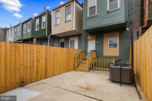 back of house featuring brick siding, central air condition unit, a patio, and fence