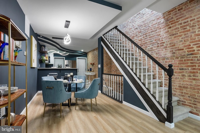 bar with stairway, wood finished floors, baseboards, and brick wall