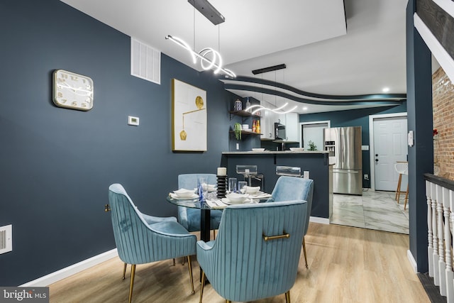 dining space with visible vents, baseboards, and light wood-style flooring