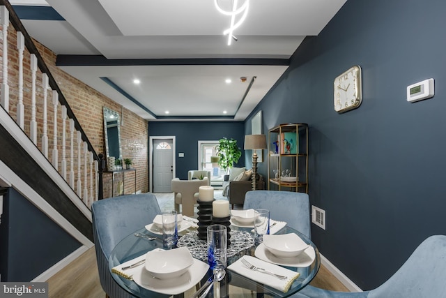 dining area featuring visible vents, brick wall, baseboards, stairs, and wood finished floors