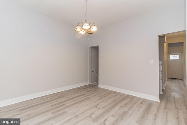 unfurnished dining area featuring an inviting chandelier, baseboards, and light wood-style floors