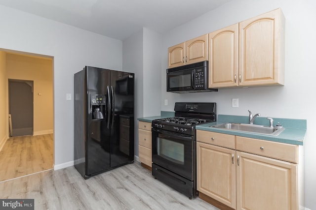 kitchen with baseboards, light brown cabinetry, light wood-type flooring, black appliances, and a sink