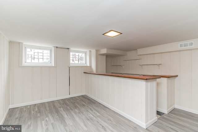 bar featuring light wood-style floors, visible vents, and baseboards