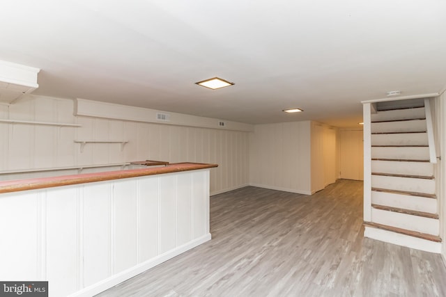 bar with visible vents, light wood-style flooring, and stairs